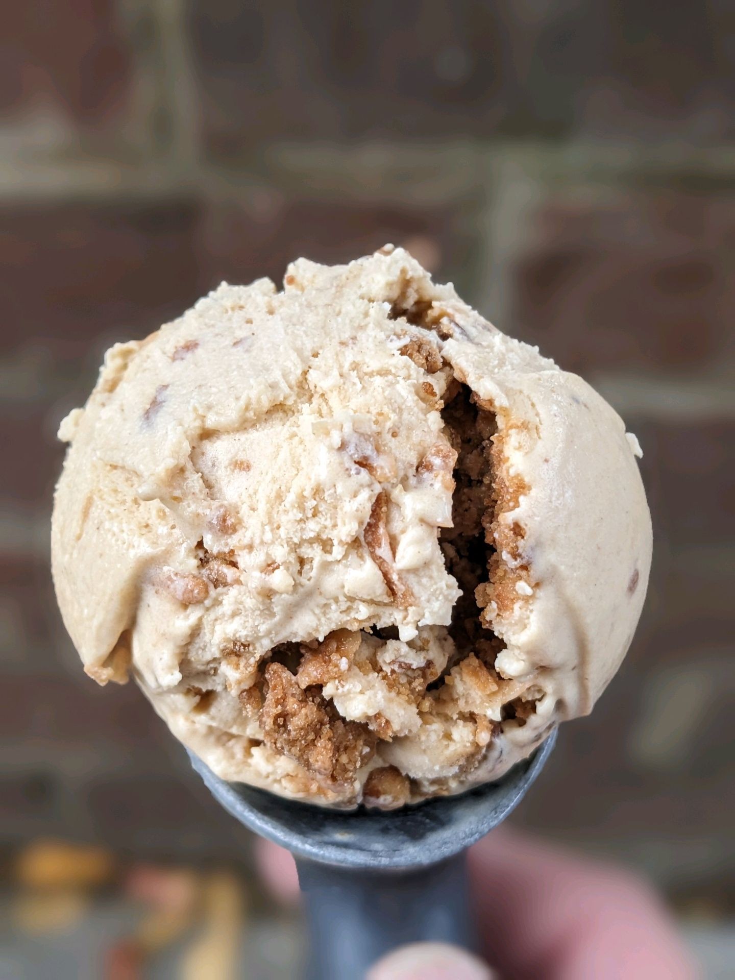 Sweet potato casserole ice cream, with chunks of pecan topping set on a brick wall background 